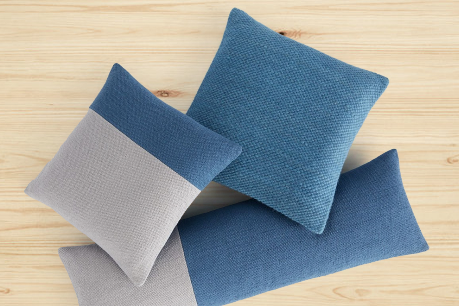 A group of blue and grey throw pillows on a wood table