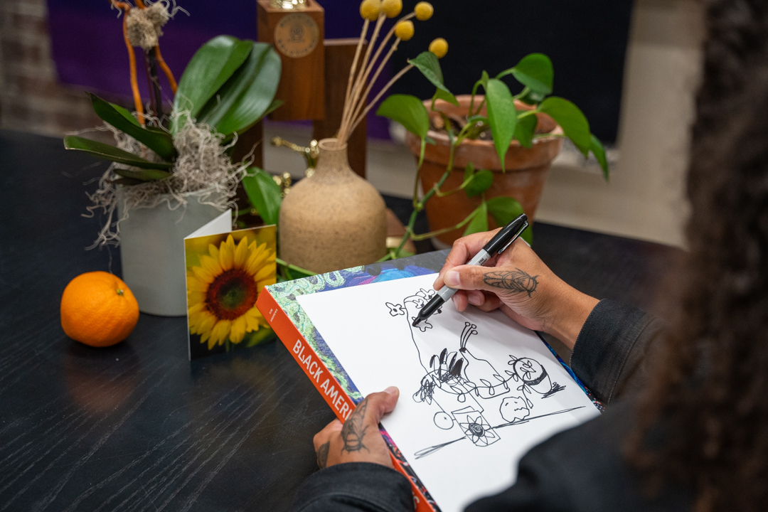 Over the shoulder view of someone drawing a stll life with the still life scene in the background