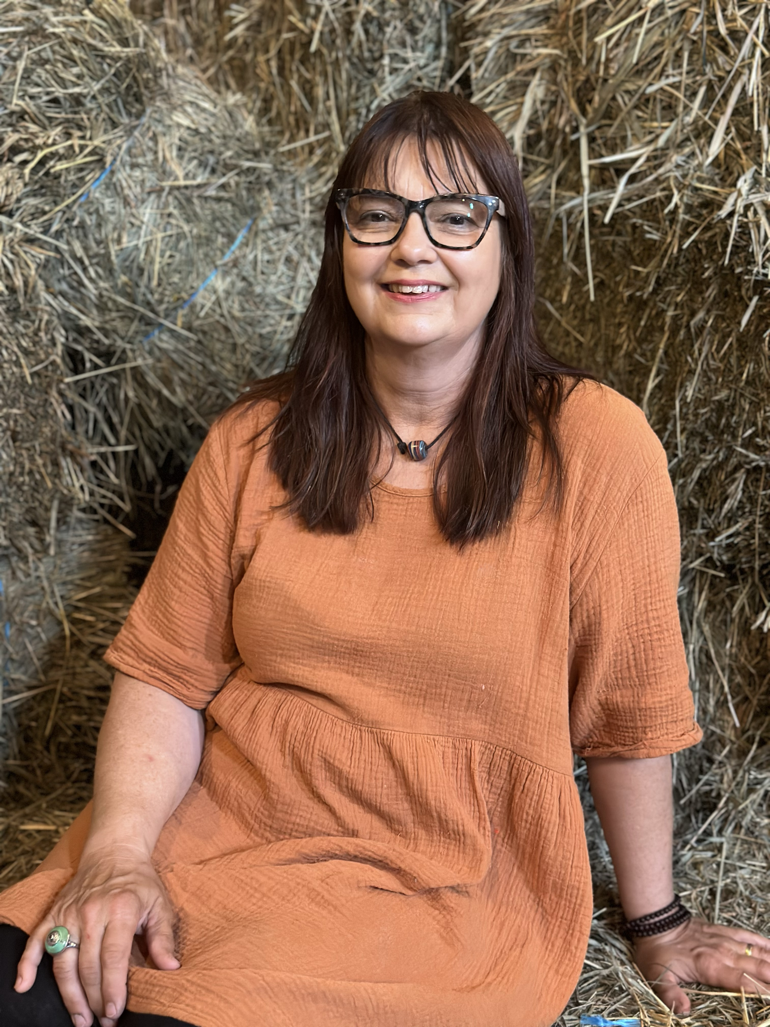 Populus Fund 2024 Grantee Trudie Teijink sits in a hay stack and smiles at the camera