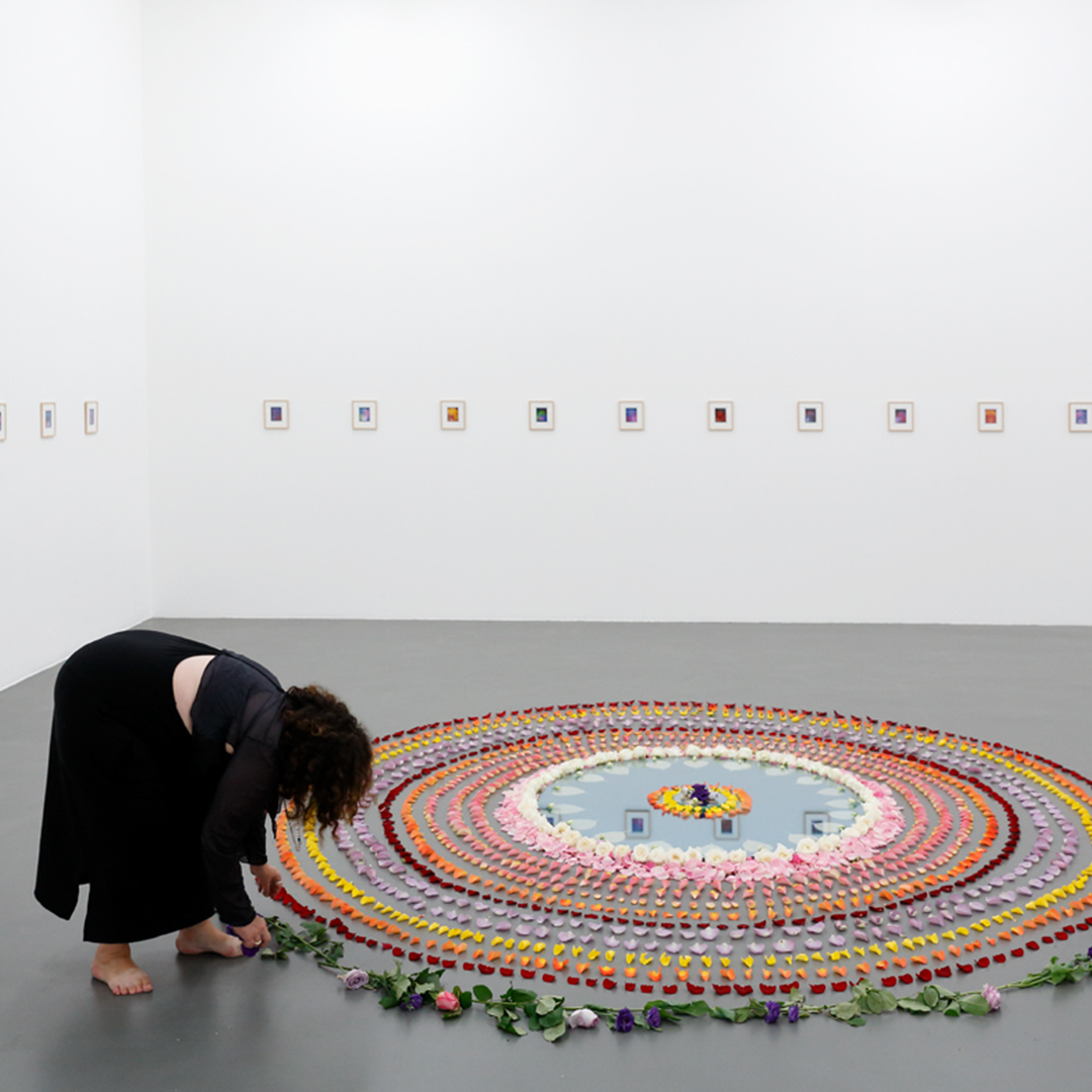 Populus Fund Grantee Fiendish Plots an artist arrangles flowers into a circular shape in a gallery