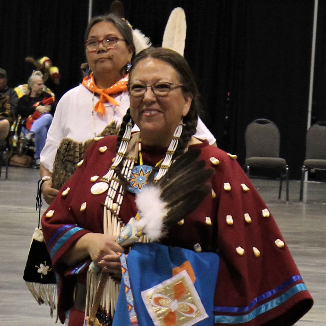 Populus Fund Grantee Valery Killscrow Copeland who is Oglala Sioux wheres Native Amerian regalia and smiles at the camera